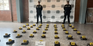 Foto de dos policías frente a paquetes de mariuana incautados en el aeropuerto.