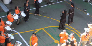 Foto que muestra personas reunidas en un patio con tambores y pancartas