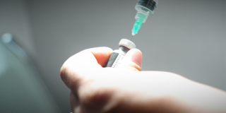 Foto de una mano agarrando una dosis de una vacuna 