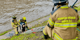 Bomberos rescatando a dos hombres que cayeron al canal de la avenida NQS.