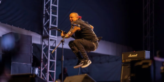 Imagen de un artista en tarima de Rock al Parque tocando una guitarra.