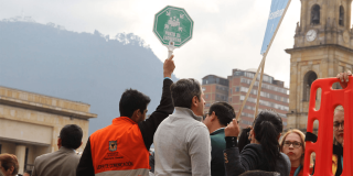 Personal de logística y participantes reunidos en una plaza del centro de Bogotá durante un simulacro. Una persona sostiene en alto una señal verde de “Punto de encuentro”, mientras alrededor se observan varios asistentes. Imagen de referencia para el Simulacro Bogotá 2026.