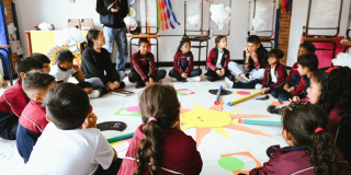 Foto que muestra estudiantes sentados en el piso y hablando entre ellos