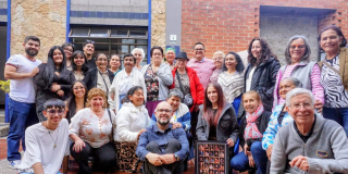 Foto de un grupo de personas de diferentes edades posando para una fotografía frente a un edificio.