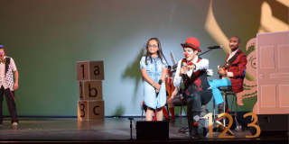 Un señor disfrazado de payaso arrodillado enfrente de una niña 