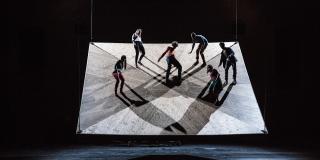 Un escenario, seis personas actúan sobre una lamina en movimiento