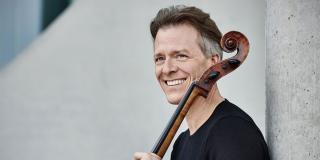 El músico Alban Gerhardt sonriendo con su instrumento en la mano