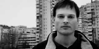 Hombre joven de cabello oscuro posa mirando a la cámara.