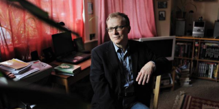 Un hombre rubio y delgado posa ante la cámara.