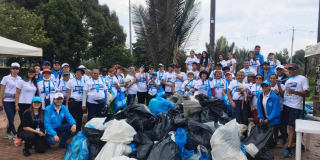 Grupo de personas posan con bolsas de basura.