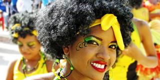 Mujer sonriente de piel morena y cabello negro rizado.