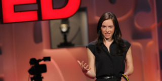 Mujer blanca de pelo castaño habla en una charla.