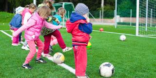 Varios niños pequeños jugando fútbol en una cancha de fútbol