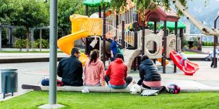 Un parque con varios padres vigilando a sus niños en un juego de parque 