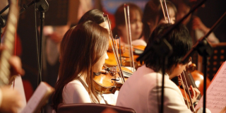 Foto ligeramente desenfocada de un grupo de jóvenes interpretando el violín.