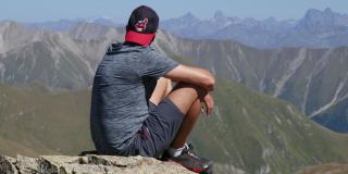 Foto de stock de un hombre joven mirando al horizonte lleno de montañas. 