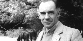 Hombre mayor, ligeramente calvo posa sonriente. Foto en blanco y negro.