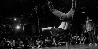 Foto en blanco y negro de hombre haciendo una pirueta de break dance.