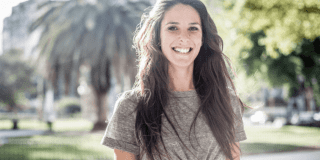Retrato de mujer delgada de cabello que posan sonriente a la cámara.