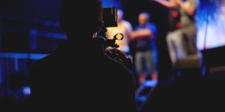 Un hombre con una cámara grabando a varios actores en escena 