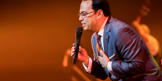 Foto de Gilberto Santa Rosa, vestido de traje entero, en medio de una presentación.