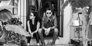 Imagen de un hombre y una mujer sentados a la entrada de una puerta