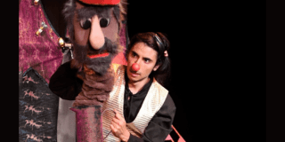 Imagen de un hombre que dialoga con Anuki un títere de gran formato 