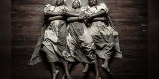 Imagen de tres mujeres afrocolombianas acostadas y cogidas de las manos entrecurzadas