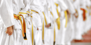 Imagen de varios niños en fila vestidos con traje blanco y cinturon amarillo de practica de karate