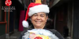 Imagen de beneficiaria con gorro de navidad y mercado por el Banco de Alimentos de Bogotá