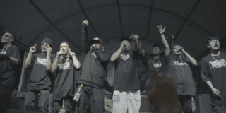Imagen de una banda de rap en un escenario.