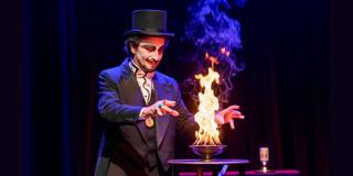 Imagen donde se aprecia el Ilusionista haciendo un acto de magia donde prende fuego