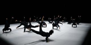 Imagen de los bailarines en la puesta en escena, ellos visten trusas negras