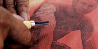 Imagen de una mano trabajando el grabado de una imagen de un hombre en una pieza textil 