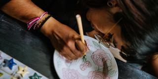 Imagen de mujer pintando sobre un plato de cerámica 