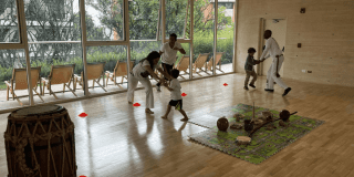 Imagen de varios niños junto a su profesor tomando una clase de capoeira.