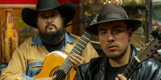 Foto de dos hombres con sombrero y uo coonuna guitarra 