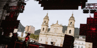 Imagen de una mujer dj tocando una consola al frente de la iglesia en la Plaza de Bolívar