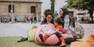 Imagen de 2 mujeres y una niña sentadas en una silla puff en actividad al aire libre en el Centro de Bogotá