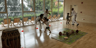 Imagen de varios niños junto a su profesor tomando una clase de capoeira.