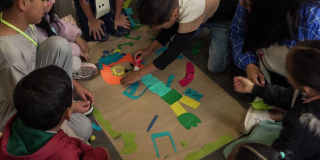 Imagen de grupos de niños creando un personaje con recortes en una cartelera