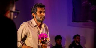 Foto de un hombre con unas flores rosadas en las manos 