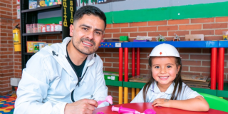 Imagen de un hombre y una niña con casco jugando sobre una mesa en las bibliotecas públicas de Bogotá