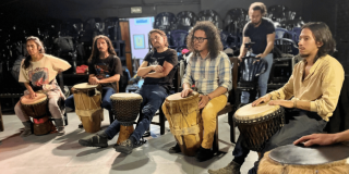 Imagen de varias personas disfrutando la experiencia, cada uno con un tambor.