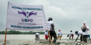 Imagen de personas en una playa con una bandera de Unidad de Búsqueda de Personas dadas por Desaparecidas (UBPD)