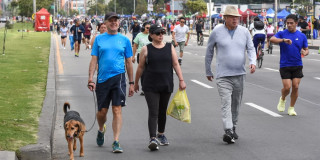 Personas caminan, trotan y se desplazan en bicicleta por una vía principal cerrada al tráfico durante jornada de Ciclovía en Bogotá