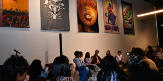 Imagen de varias personas en una sala de exposición sentadas en una charla.