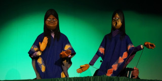 Imagen de dos marionetas con rasgos indígenas vestidas con mantas azules 