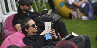 Imagen de dos hombres leyendo un libro sobre un sillón en picnic literario 2025