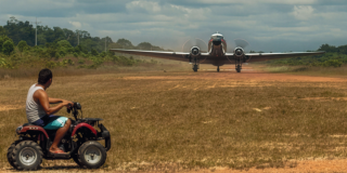 Imagen un avión despegando y un hombre sobre una cuatrimoto